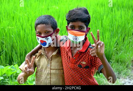 I bambini rurali indossano una maschera colorata che rappresenta due diversi paesi bandiera simbolica e che hanno un tempo di divertimento insieme . Foto Stock