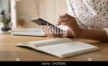 Le mani di una donna freelance che prende appunti sullo smartphone Foto Stock