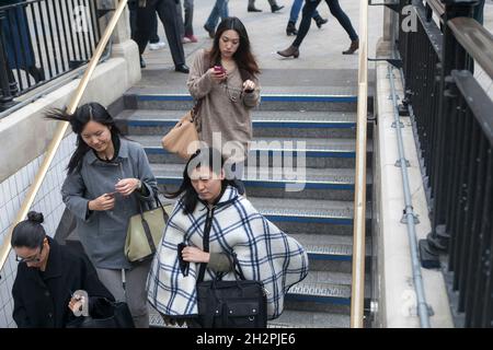 LONDRA, INGHILTERRA - Settembre 19 2021: Tre ragazze vestite alla moda in poncho e impermeabili scendono le scale della metropolitana vicino Oxford Street Foto Stock