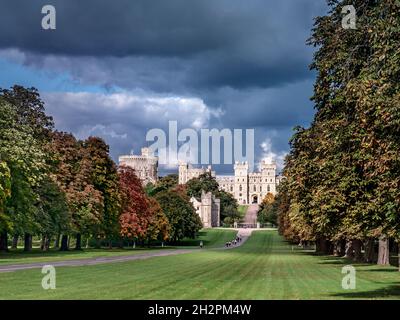 Il Castello di Windsor ha visto lungo la Long Walk con gli escursionisti, in colore autunnale con alberi drammatici di luce solare autunnale e il cielo che si staglia Berkshire UK Foto Stock