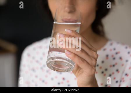 Mano di donna che tiene il vetro e beve acqua fredda fresca Foto Stock