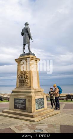 Whitby, North Yorkshire, Regno Unito – Ottobre 17 2021. I turisti che guardano il monumento commemorativo del Capitano Cook sulle scogliere nella cittadina balneare di Whitby Foto Stock