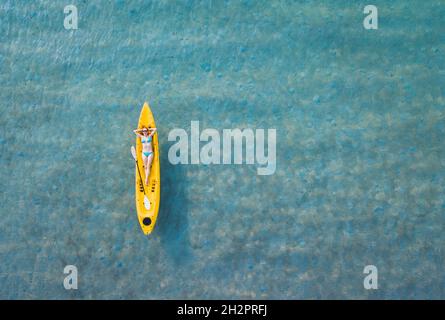 felice estate vacanze sulla spiaggia, vacanza viaggio, donna turistica in bikini relax su kayak giallo, vista aerea dall'alto Foto Stock
