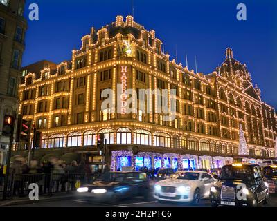 HARRODS NOTTE NATALE ACQUIRENTI LUCI SFOCATE TRAFFICO Harrods grande magazzino al crepuscolo con luci di Natale acquirenti e passando traffico sfocato Knightsbridge Londra SW1 Foto Stock