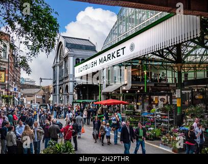 Ingresso con vista esterna del Borough Market, con bevitori all'aperto e acquirenti all'esterno, con bancarelle di prodotti e fiori, un rinomato e frequentato mercato di prodotti alimentari internazionali al dettaglio, il London Bridge Southwark London UK Foto Stock