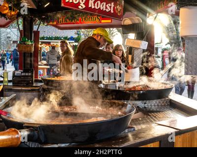 South Bank mercato tedesco di Natale cibo Hog Roast da asporto al fresco caldo salsicce a vapore carni in una bancarella di cibo e visitatori Londra UK Foto Stock