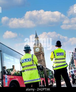 Gli ufficiali della polizia di Londra indossano caschi e giacche ad alta visibilità sulla Westminster Street duty back view al Westminster Bridge Houses of Parliament London UK Foto Stock