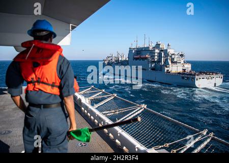 GOLFO ARABO (ott 23, 2021) Seaman Jude Chukwuobasi si prepara a segnalare alla nave da carico e munizioni a secco USNS Wally Schirra (T-AKE 8) a bordo della nave d'assalto anfibio USS Essex (LHD 2) durante un rifornimento in mare, ottobre 23. L'Essex e l'undicesima unità Marine Expeditionary sono dislocate nell'area della 5th Fleet degli Stati Uniti di operazioni a sostegno delle operazioni navali per garantire la stabilità e la sicurezza marittima nella regione centrale, collegando il Mediterraneo e il Pacifico attraverso l'Oceano Indiano occidentale e tre punti di arresto strategici. (STATI UNITI Foto Navy di Mass Communication Specialist 2a Classe Jo Foto Stock