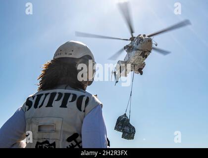 GOLFO ARABO (ott 23, 2021) CMdR. Ty Luster, agente di fornitura della nave d'assalto anfibio USS Essex (LHD 2), osserva un Aerospatiale SA 330 Puma consegnare il carico durante un rifornimento verticale-a-mare con il carico secco e la nave munizioni USNS Wally Schirra (T-AKE 8), ottobre 23. L'Essex e l'undicesima unità Marine Expeditionary sono dislocate nell'area della 5th Fleet degli Stati Uniti di operazioni a sostegno delle operazioni navali per garantire la stabilità e la sicurezza marittima nella regione centrale, collegando il Mediterraneo e il Pacifico attraverso l'Oceano Indiano occidentale e tre punti di arresto strategici. (STATI UNITI Navy pho Foto Stock