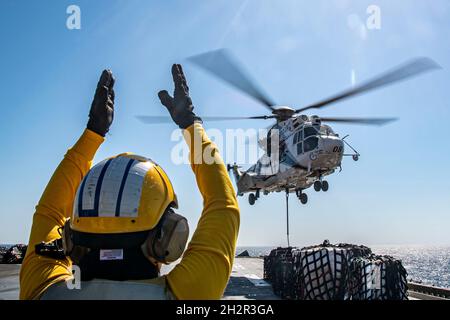 GOLFO ARABO (ott 23, 2021) Aviation Boatswain’s Mate (Handling) 3rd Class Deandrea Doe segnala ad un Aerospatiale SA 330 Puma sul ponte di volo della nave d’assalto anfibio USS Essex (LHD 2) durante un rifornimento verticale in mare con la nave da carico e munizioni a secco USNS Wally Schirra (T-AKE 8), ottobre 23. L'Essex e l'undicesima unità Marine Expeditionary sono dislocate nell'area della 5th Fleet degli Stati Uniti di operazioni a sostegno delle operazioni navali per garantire la stabilità e la sicurezza marittima nella regione centrale, collegando il Mediterraneo e il Pacifico attraverso l'Oceano Indiano occidentale e tre stra Foto Stock