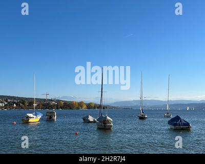 Piccole barche a vela ancorate sul lago di Zurigo in Svizzera. Le navi sono coperte di teloni per proteggerle dalle intemperie. Foto Stock