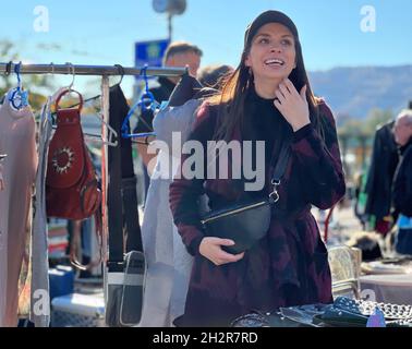 La giovane donna si diverte e si diverte al mercato delle pulci di Zurigo, in Svizzera. Sta ispezionando le merci e ha molto tempo in giorno di sole. Foto Stock