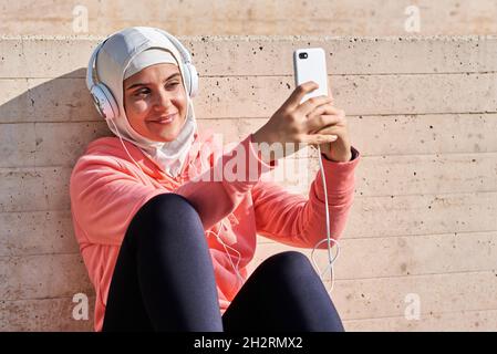 Giovane musulmana con cuffie che fa una pausa Foto Stock