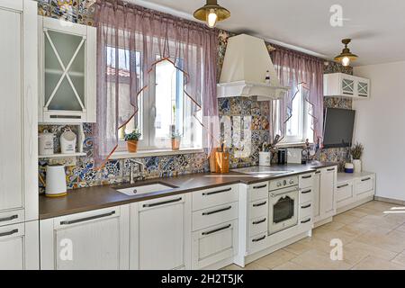 Ampia cucina con mobili bianchi e piastrelle colorate in stile classico contemporaneo Foto Stock
