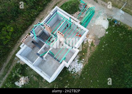 Vista aerea di telaio incompiuto di casa privata con pareti aerate in calcestruzzo leggero e travi in legno tetto in costruzione. Foto Stock