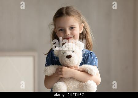 Ritratto di sorridente bambina coccolare il giocattolo soffice preferito. Foto Stock