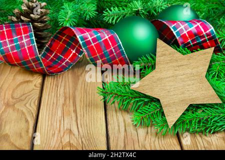 Decorazioni natalizie di colore rosso verde con rami di abete e stella su sfondo in legno Foto Stock