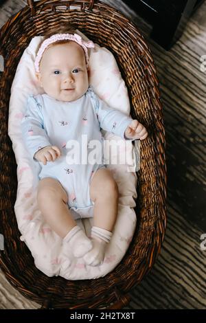 Foto dall'alto dell'adorabile bimbo sdraiato nel cestino di vimini sul pavimento. Foto Stock