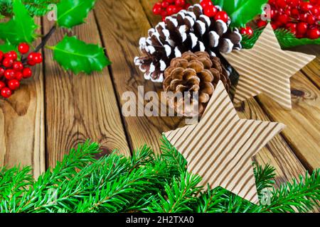 Decorazioni natalizie naturali con rami di abete e agrifoglio su sfondo in legno Foto Stock