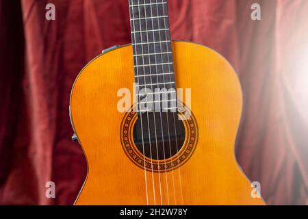 Chitarra classica su sfondo rosso. Concetto di chitarra acustica. Foto Stock