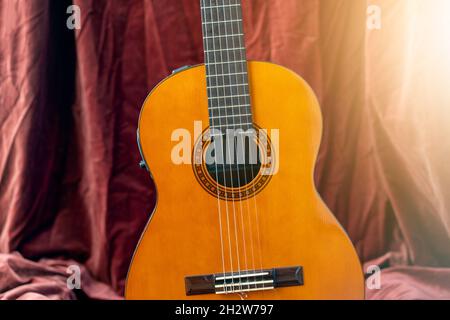 Chitarra classica su sfondo rosso. Concetto di chitarra acustica. Foto Stock