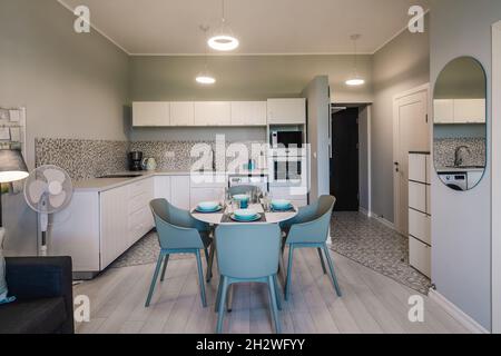 Interni moderni di appartamenti di lusso in tonalità di grigio. Cucina elegante. Comodo divano. Tavolo da pranzo. Foto Stock