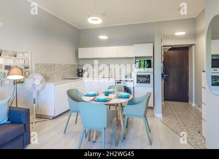 Interni moderni di appartamenti di lusso in tonalità di grigio. Cucina elegante. Comodo divano. Tavolo da pranzo. Foto Stock