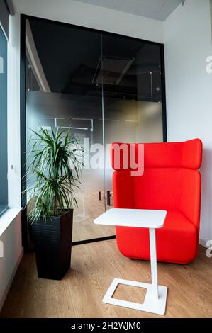 Mini poltrona rossa e un piccolo tavolo bianco in un'azienda moderna Foto Stock