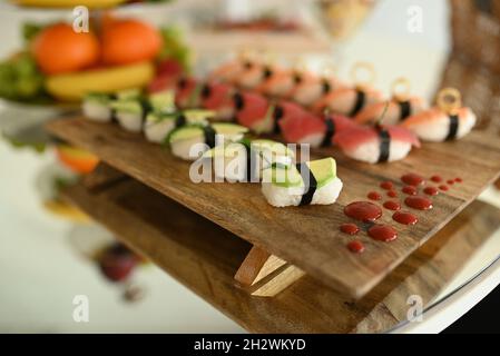 Set di vari tipi di sushi su un piatto di legno. Set grande con sushi e rotoli. Sushi e panini, pesce, verdure con wasabi e zenzero. Foto Stock