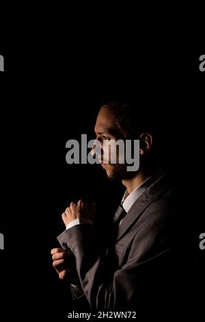 Un giovane uomo d'affari in un grigio intelligente che guarda la fotocamera fissando i suoi polsini Foto Stock