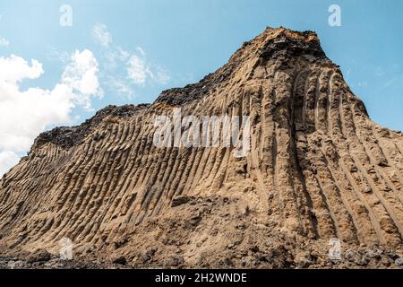 Impronte della benna dell'escavatore. Solchi dell'escavatore. Strisce da lavori di attrezzature per cave pesanti. Solco in primo piano dall'escavatore sulla terra come sfondo Foto Stock