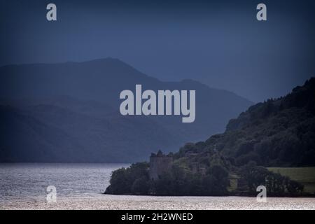 Un pomeriggio buio mentre il tempo torrido passa attraverso le Highlands dona un'atmosfera molto diversa alla vista attraverso Urquhart Bay verso il suo famoso castello. Foto Stock