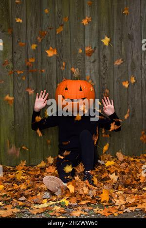 La ragazza sedette a terra con la testa di zucca Foto Stock