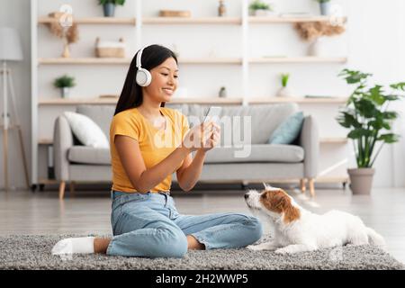Ragazza asiatica allegra scattando la foto del suo cane carino Foto Stock