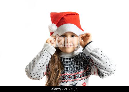 Ritratto di sorridente ragazza in maglia bianca Natale maglione con renna reggendo Babbo Natale cappello, isolato su sfondo bianco Foto Stock