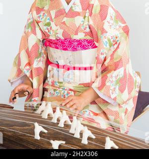 Donna irriconoscibile che indossa un kimono che suona un koto, un tradizionale strumento a corda giapponese. Foto Stock