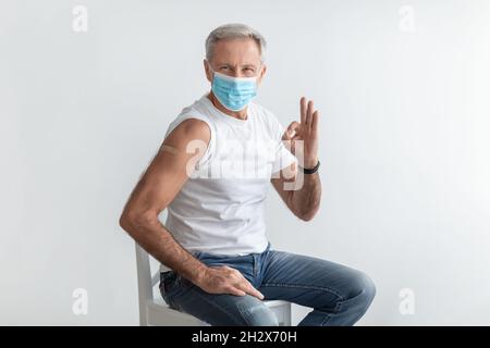 Vaccinato Senior Man gesturing OK dopo la vaccinazione contro Covid-19, Studio Foto Stock