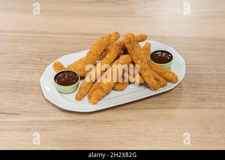 Ampia porzione di strisce di pollo croccanti impanate con panko e uova fritte in olio d'oliva, accompagnate da salsa barbecue e servite come tapas Foto Stock