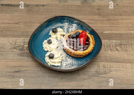 deliziosa torta di cheesecake individuale con marmellata di mirtilli, fragole e panna montata con zucchero a velo Foto Stock