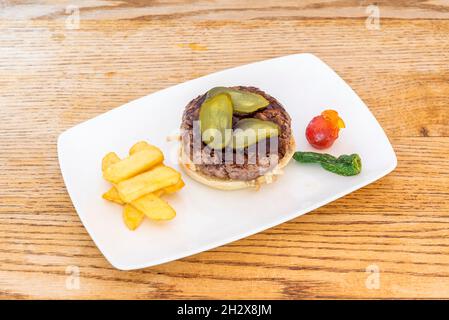 Hamburger di manzo con salsa Chimichurri argentina, Pickles sottaceto, fritte francesi fatte in casa e peperoni verdi fritti Foto Stock