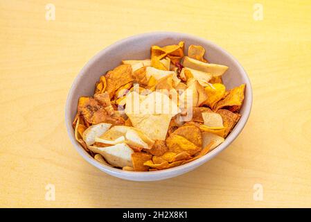 Antipasti ciotola di patatine, patate dolci, piantane e altre verdure su tavola gialla Foto Stock