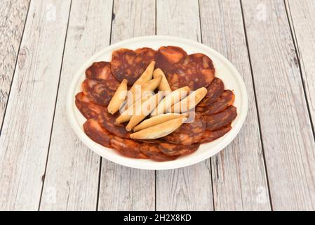 Tapas spagnole di chorizo iberico alimentato con ghiande con picchi su un piatto bianco da asporto Foto Stock