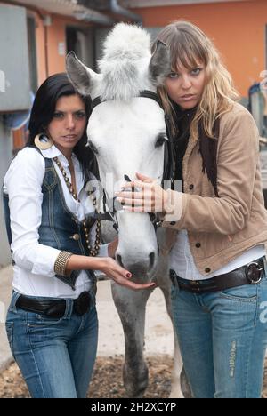 le jockey femminili nell'arena preparano i loro cavalli per uscire per un trotto Foto Stock