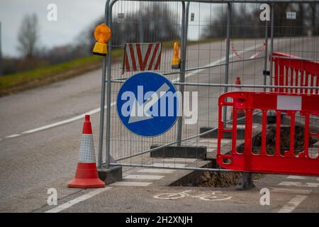 Riparazione su una corsia per biciclette. Con un recinto limitato buca scavata durante le riparazioni su strada lungo il percorso ciclabile. Segnale di bypass Foto Stock