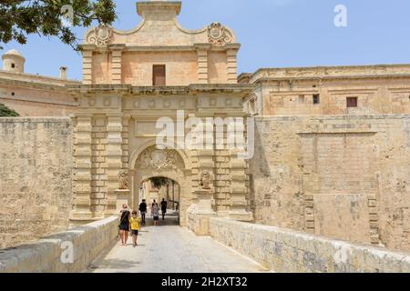 I turisti camminano attraverso il portale barocco della porta Mdina, conosciuta anche come la , che è la porta principale della città fortificata Foto Stock