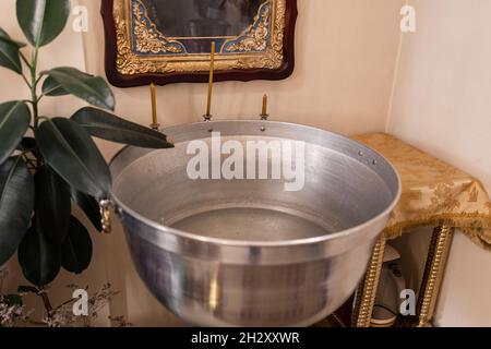 una ciotola di battesimo nella chiesa con candele Foto Stock