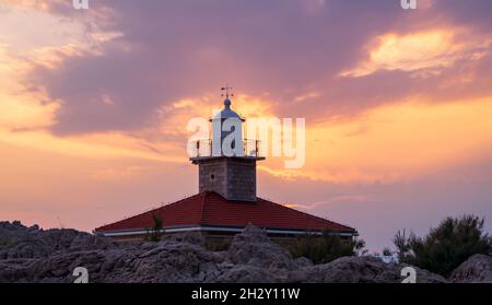 Faro al tramonto con cielo epico Foto Stock