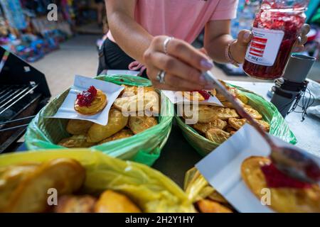 Formaggio di pecora affumicato chiamato nelle montagne polacche 'Oscypek, oszczypek', servito a mano femminile con salsa di mirtilli dopo essere stato cotto al grill Foto Stock