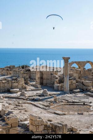 Il parapendio scivola sulle rovine della Basilica cristiana presso il sito archeologico di Kourion, Cipro. Foto Stock