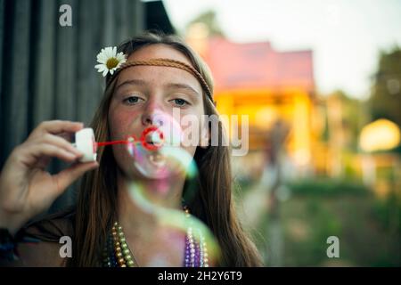 Teengirl in abiti hippie nel villaggio, soffia bolle di sapone. Foto Stock